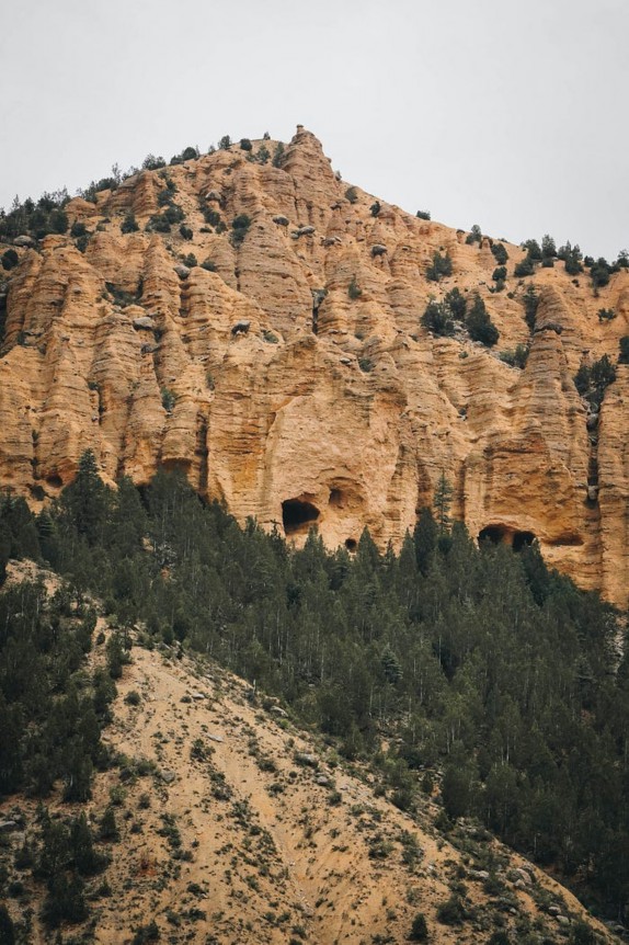 A mountainous landscape in Bamyan, Afghanistan featuring rocky cliffs and a forested area in the foreground.