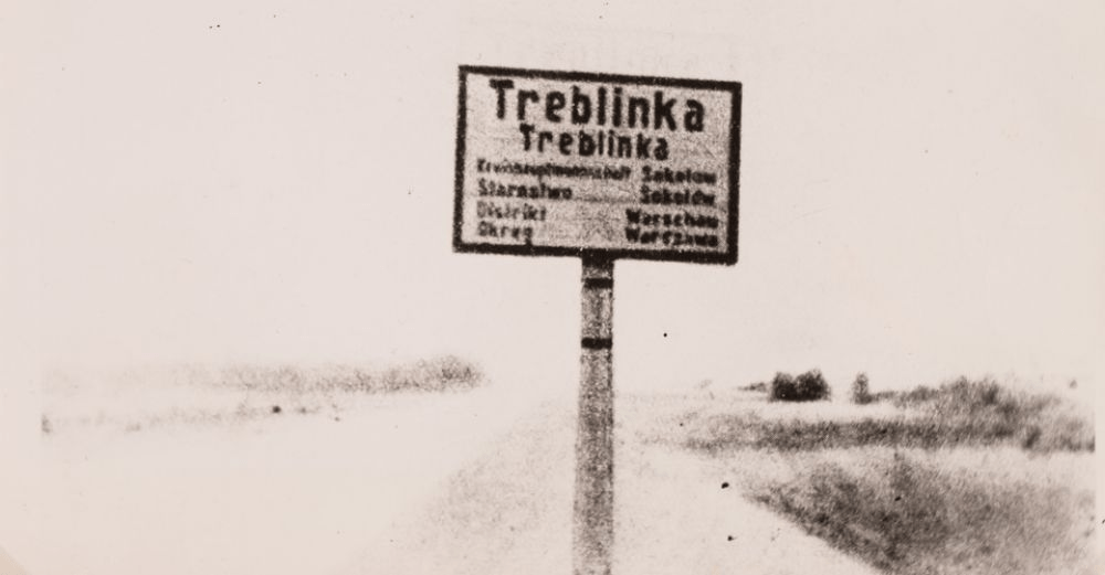 A historical sign marking the location of Treblinka, with text in Polish and German indicating the administrative details and the surrounding area.